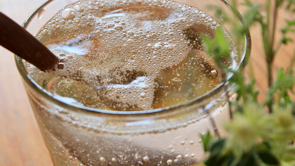Préparation d'un mocktail gin tonic avec tonic versé dans verre rempli de glaçons